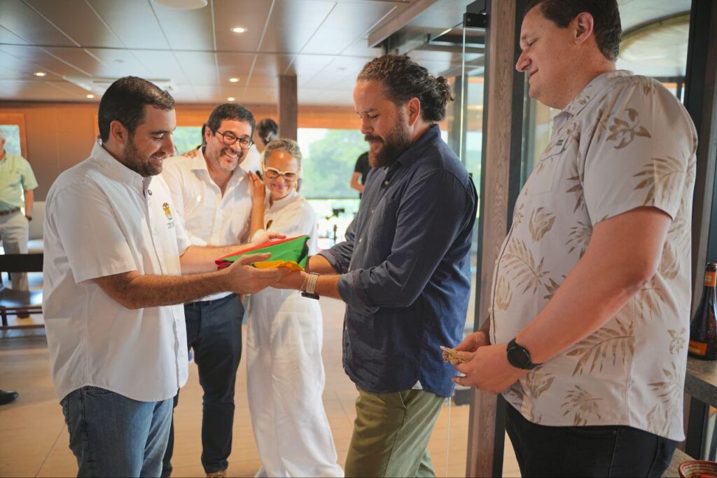 El gobernador Yamil Arana le entrega la bandera de Bolívar a Beno Aton, director ejecutivo de AmaWaterways, operador del AmaMagdalena. Observa sonriente la directora Icultur, Lina Rodríguez.